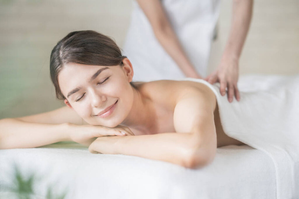 Mujer joven recibiendo un masaje en un salón de belleza en un ambiente luminoso
 - Foto, imagen