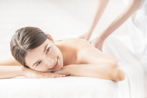 Jeune femme recevant un massage dans un salon de beauté dans une atmosphère lumineuse - Photo, image