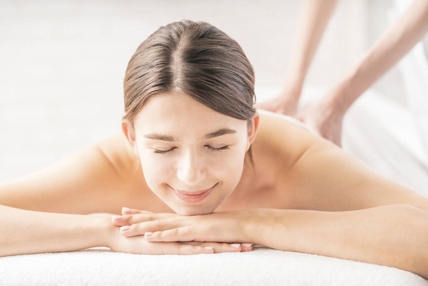 Młoda kobieta otrzymuje masaż w salonie piękności w jasnej atmosferze - Zdjęcie, obraz
