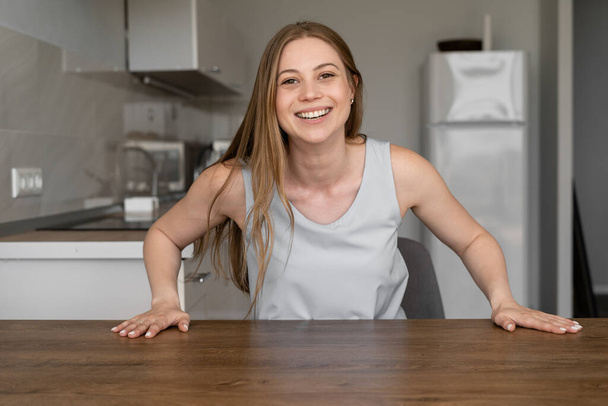 Smiling woman makes video call in her kitchen. Online chat, video communication, modern technologies concept - Foto, imagen