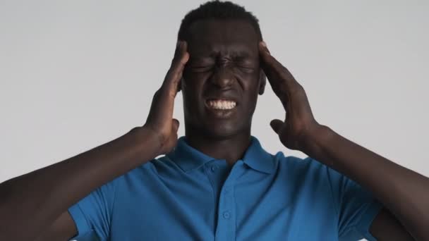 Portrait of depressed African American man emotionally showing headache over gray background. Pain expression - Imágenes, Vídeo
