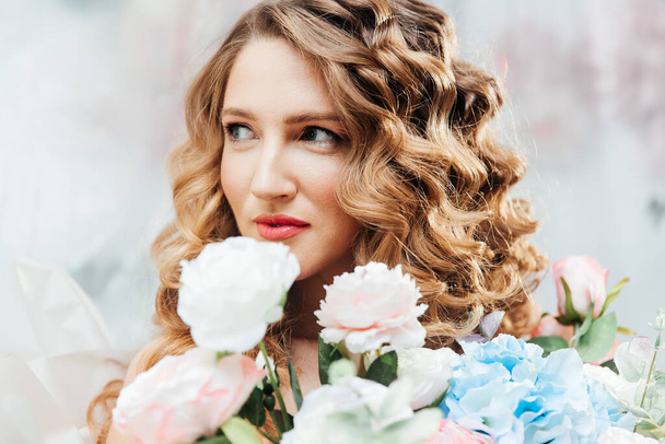 Hermosa chica con hermoso maquillaje en su cara y peinado con un gran ramo de flores de lujo, publicidad para cosmetólogos y floristas con decoradores
 - Foto, Imagen