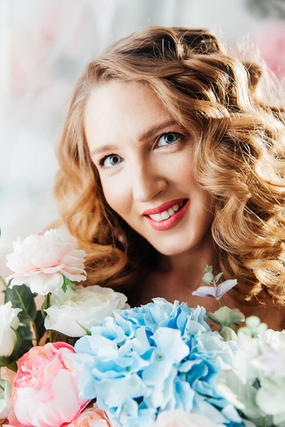 Beautiful girl with beautiful makeup on her face and hairstyle with a large luxurious bouquet of flowers, advertising for cosmetologists and florists with decorators - Φωτογραφία, εικόνα