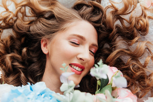 Kaunis tyttö kaunis meikki hänen kasvonsa ja kampauksen suuri ylellinen kukkakimppu, mainonta kosmetologit ja kukkakaupat sisustajat - Valokuva, kuva