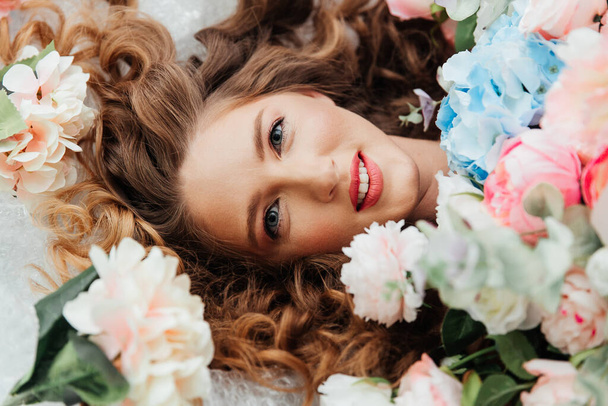 Hermosa chica con hermoso maquillaje en su cara y peinado con un gran ramo de flores de lujo, publicidad para cosmetólogos y floristas con decoradores
 - Foto, Imagen
