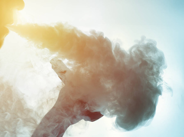 dampen van een man met een mechanische mod en uitademt grote hoeveelheden rook of stoom - Foto, afbeelding
