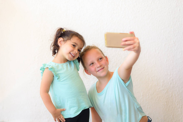 Happy children making selfie.Two adorable little sisters taking photo of himself. - Фото, изображение