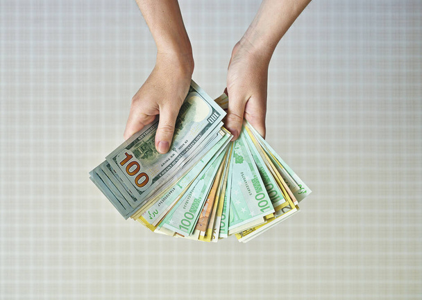 Mão de mulher segurando notas de dólar e euro. conceito sobre o tema do dinheiro
 - Foto, Imagem