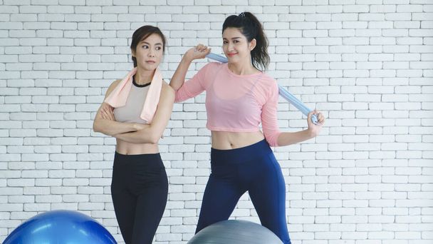 Un grupo de mujeres asiáticas jóvenes que usan ropa deportiva está hablando de deportes en el gimnasio después de hacer ejercicio haciendo estiramientos con posturas de yoga
. - Foto, Imagen