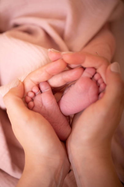 Baby feet in mother hands. Tiny Newborn Baby's feet on female Heart Shaped hands closeup. Mom and her Child. Happy Family concept. Beautiful conceptual image of Maternity. Close up image. - Photo, Image