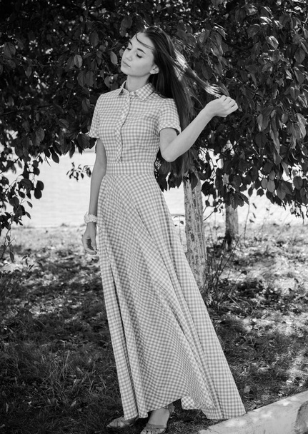 Kaunis nuori laiha tyttö kävelee ympäri kaupunkia pitkässä mekossa häkissä ja nauttii päivästä - Valokuva, kuva