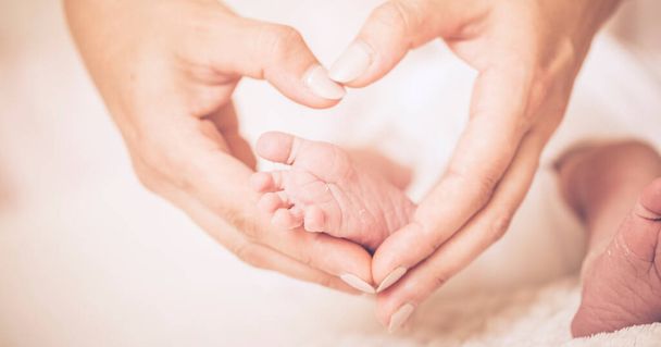 Yeni doğmuş bebek ayaklar anne ve babanın ellerinde, güzel bir kalp şeklinde.. - Fotoğraf, Görsel