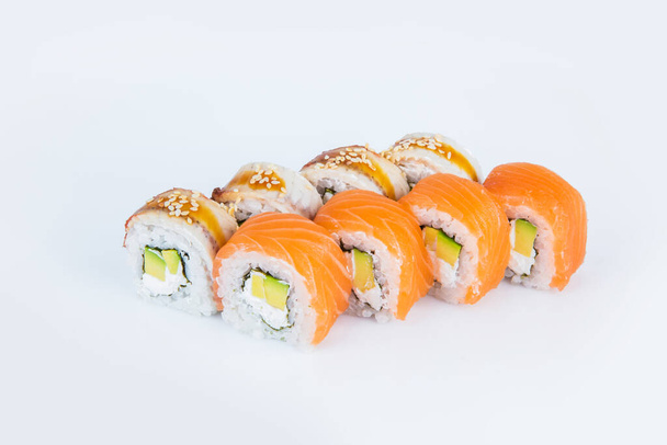 Japanese Sushi Roll with avocado, Philadelphia cream cheese with salmon and eel on top. isolated on gray background. Served with Unagi sauce and sesame seeds seeds. Asian dish Menu isolation. - 写真・画像