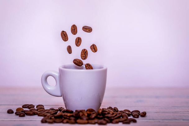 Pörkölt kávébab esik kávéscsésze a csészealj fehér háttér, friss és világos tapéta koncepció. - Fotó, kép