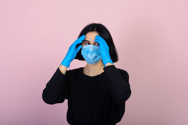 A fehér lány kék színű védő maszkban. Portré rózsaszín háttérrel. Vírus és szennyezésvédelmi koncepció. - Fotó, kép
