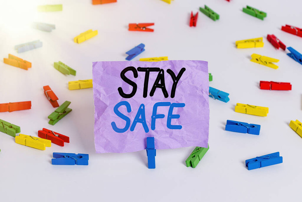 Napisz notatkę pokazującą, że jesteś bezpieczna. Biznesowe zdjęcie pokazujące bezpieczne przed zagrożeniem niebezpieczeństwem, uszkodzeniem lub miejscem do przechowywania przedmiotów Kolorowe szpilki do ubrań puste przypomnienie białe piętro tło biuro. - Zdjęcie, obraz