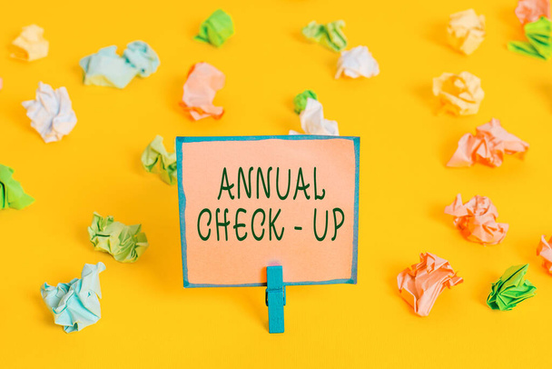 Word writing text Annual Checkup. Business concept for yearly reproductive health visit with a health care provider Colored crumpled papers empty reminder white floor background clothespin. - Photo, Image