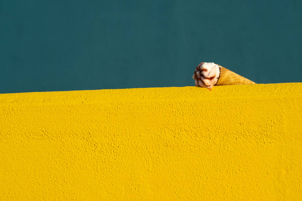 Морозиво з конусом тане влітку з температурою сонця на жовтому і синьому тлі. Концепція відпустки
 - Фото, зображення
