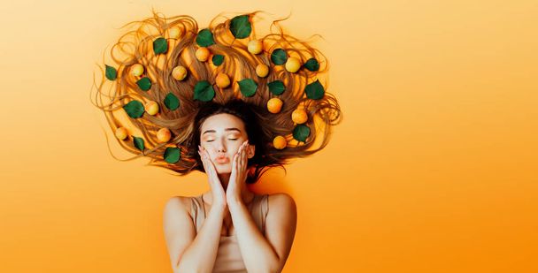 pretty girl lying on background with apricots on long hair, concept female mood, face of young woman kiss top view - Fotoğraf, Görsel