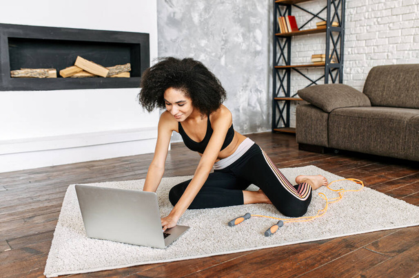 Biracial girl with a laptop is practicing yoga - Фото, зображення