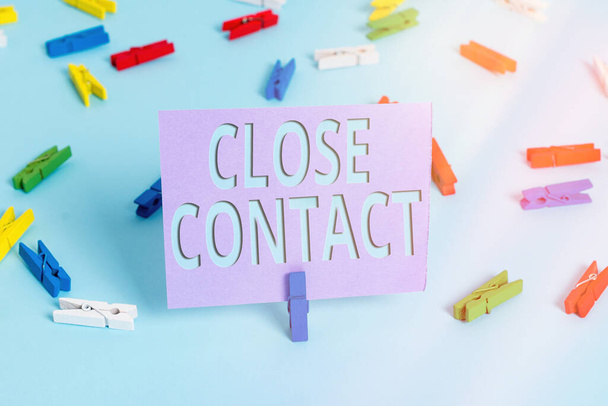 Handwriting text writing Close Contact. Concept meaning having a history of direct exposure to a casepatient Colored clothespin papers empty reminder blue floor background office pin. - Photo, Image