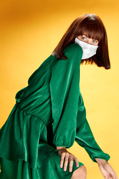 Nainen muoti mekko poseeraa lääketieteellinen naamio virus covid-19 - Valokuva, kuva