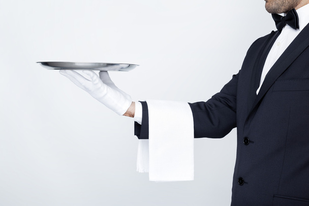 Professional waiter holding empty silver tray - Foto, afbeelding
