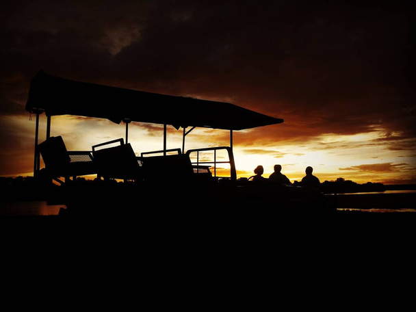 Ein Safari-Auto vor einem afrikanischen Sonnenuntergang. Foto aufgenommen in Süd-Luangwa, Sambia. - Foto, Bild
