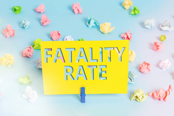 Text sign showing Fatality Rate. Conceptual photo calculated number of deaths over a specific range of period Colored crumpled papers empty reminder blue floor background clothespin. - Photo, Image