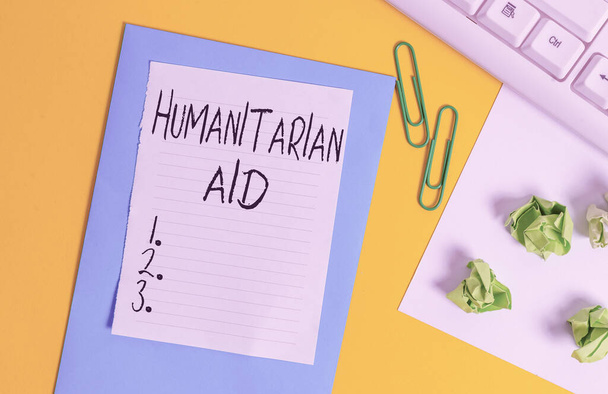 Word writing text Humanitarian Aid. Business concept for immediate assistance provided after natural and manmade disaster Flat lay above empty copy space white paper with paper clips on the table. - Photo, Image