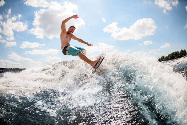 energetic male wakesurfer rides wave on board - Photo, Image