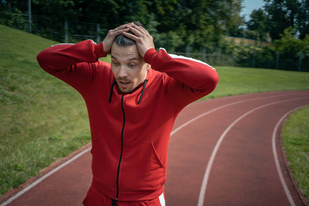 exhausted athlete resting on track after running or workout exercising outdoor - Photo, image