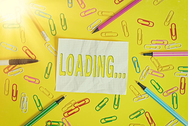 Writing note showing Loading.... Business photo showcasing applying an extra amount to offset a particular element Flat lay above empty paper with pencils and paper clips. - Photo, Image