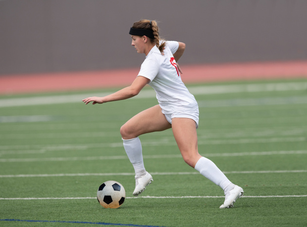 Young attractive athletic girl playing soccer in a game - Photo, Image