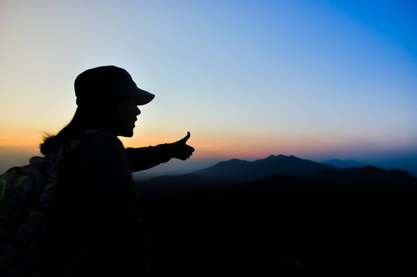 силует жінка мандрівник дивитися вид захід сонця на гору в момент щастя.
. - Фото, зображення