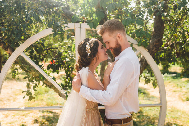 Wood Hand Made Welcome Wedding Decoration. Rustic wedding photo zone. Decor garden for wedding ceremony. Beautiful young sensual couple newlyweds in a romantic place, apple orchard summer. - Foto, afbeelding