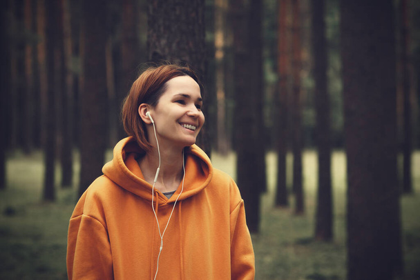 Young pretty girl with earphones. Hipster woman outdoor portrait - Фото, изображение
