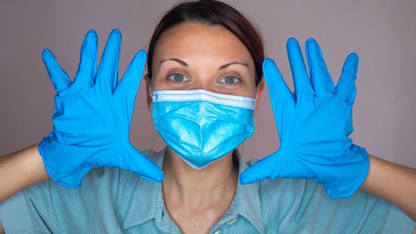 Portret kobiety w niebieskiej masce medycznej i lateksowych rękawiczkach. - Zdjęcie, obraz