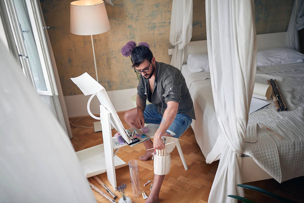 Young handsome painter painting in his bedroom - Foto, afbeelding