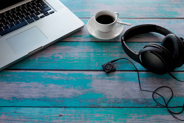 Laptop, koptelefoon, muziekspeler, zwarte koffie op blauwe houten tafel. Met kopieerruimte. Bedrijfsconcept. - Foto, afbeelding