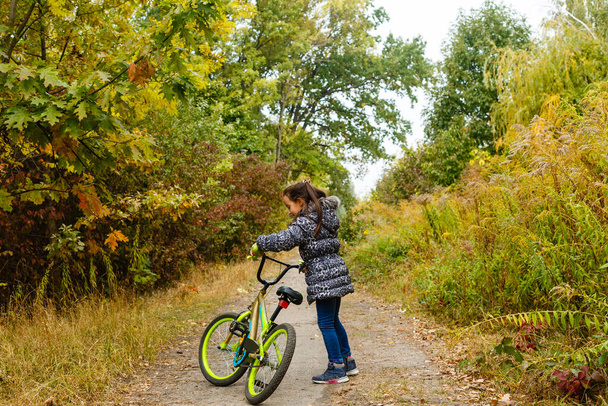Entzückendes Mädchen, das an einem schönen Herbsttag Fahrrad fährt - Foto, Bild