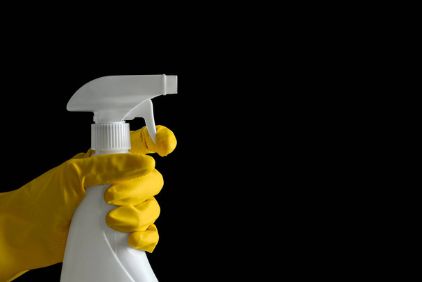 Person in gloves spraying detergent on black background, closeup. Space for text - 写真・画像