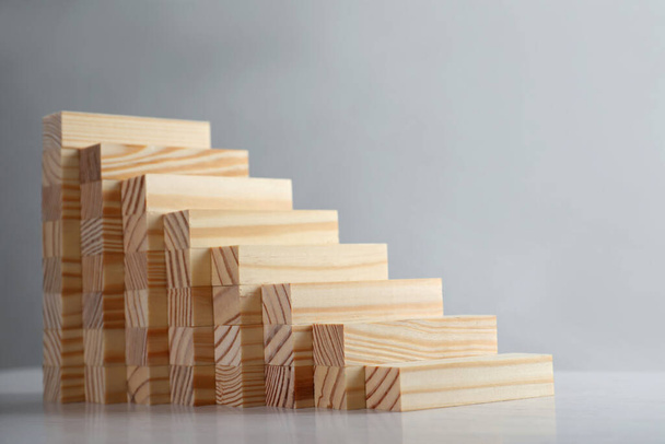 Steps made with wooden blocks on light background, space for text. Career ladder - Foto, Imagen