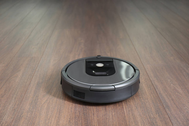 Modern robotic vacuum cleaner on wooden floor - 写真・画像