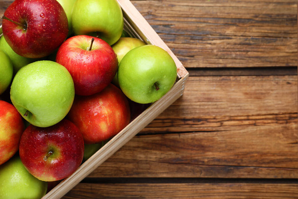 Ripe juicy apples in wooden crate on wooden table, top view. Space for text - Fotografie, Obrázek