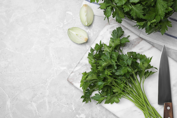 Marble board with fresh green parsley and knife on grey table, flat lay. Space for text - 写真・画像