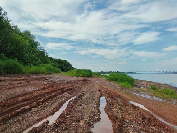 písečný břeh řeky se zatopenými cestami z dopravy proti modré obloze - Fotografie, Obrázek