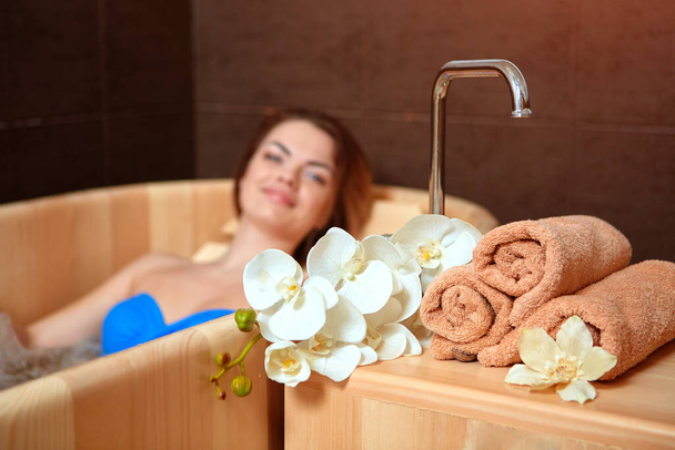A woman who has Spa treatment and recreation in a wooden hot tub made of cedar. - Φωτογραφία, εικόνα