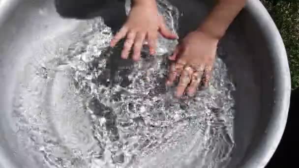 Το παιδί πλένει τα χέρια του σε καθαρό νερό μέσα στη λεκάνη. Καλοκαίρι διασκέδαση - Πλάνα, βίντεο