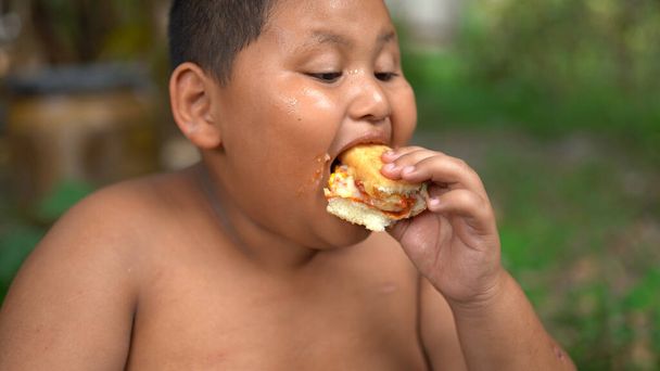 Asyalı Şişko Çocuk çok kilolu. Pizza yiyor. - Fotoğraf, Görsel